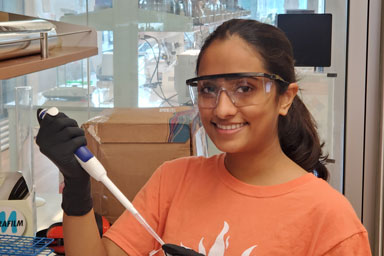 Pictured is a student holding a baster in goggles and gloves